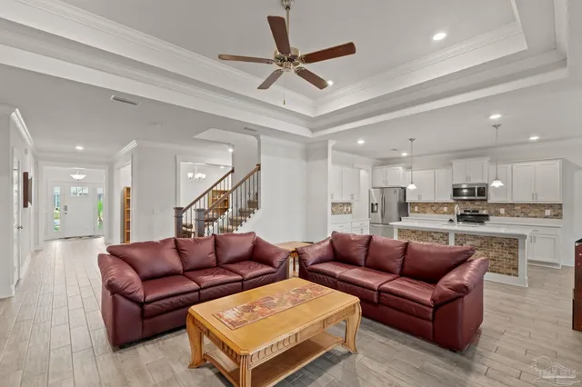 a living room with furniture kitchen view and a ceiling fan