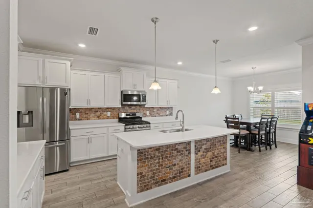 a large kitchen with kitchen island a dining table chairs stainless steel appliances and wooden floor