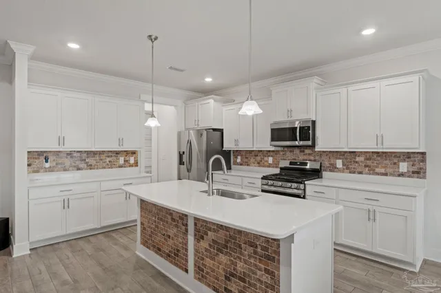a kitchen with stainless steel appliances a sink a stove a microwave a center island and cabinets