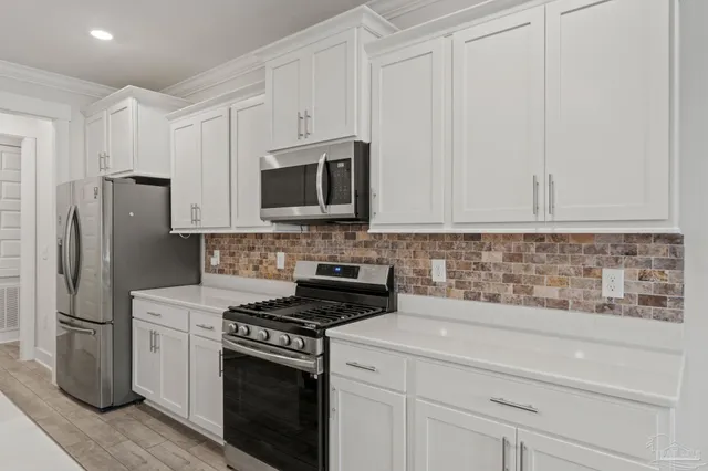 a kitchen with stainless steel appliances white cabinets and a stove a refrigerator with white cabinets