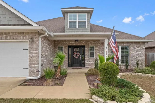 a view of a brick house with potted plants and a large window
