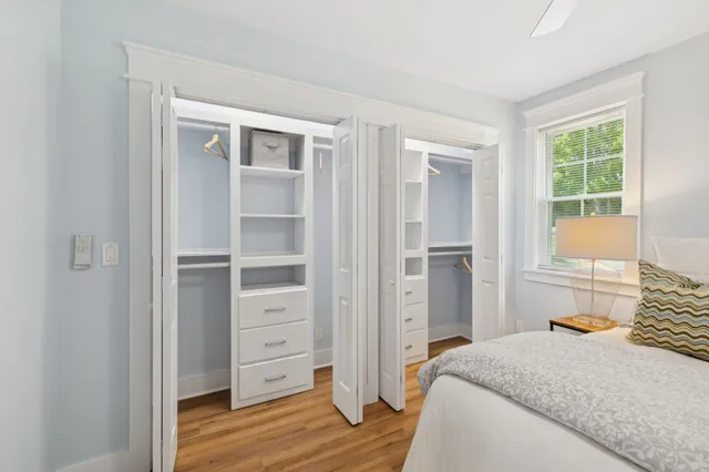 an empty room with wooden floor ceiling fan and windows