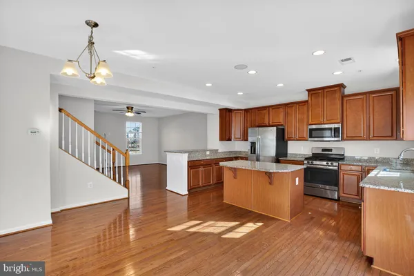 a kitchen with stainless steel appliances granite countertop wooden floors and white cabinets