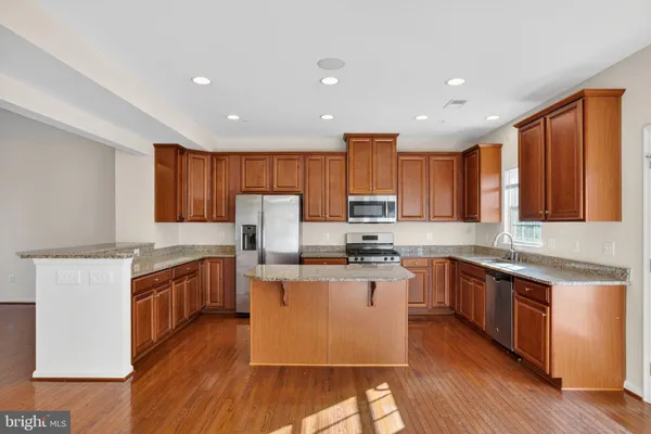 a kitchen with stainless steel appliances granite countertop wooden cabinets a sink dishwasher a stove and a refrigerator