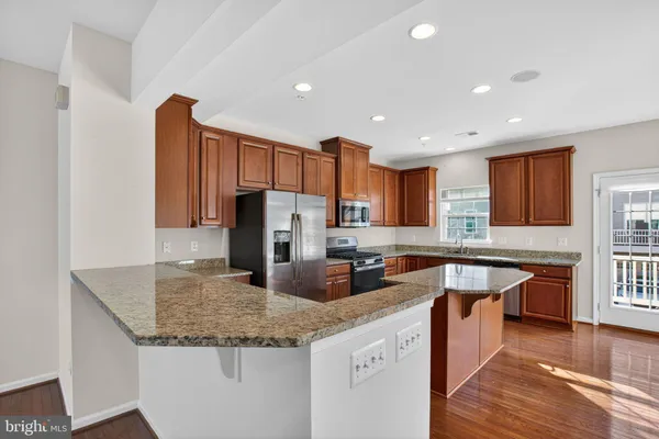 a kitchen with stainless steel appliances granite countertop a sink a stove and a refrigerator