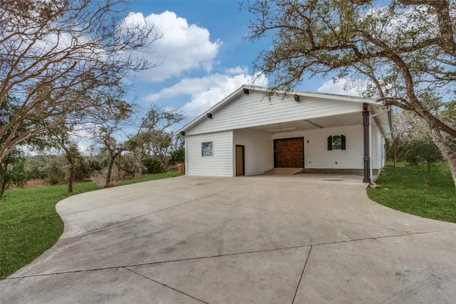 a view of a white house with a yard and large tree