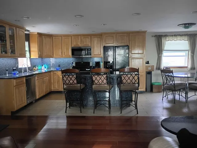 a kitchen with stainless steel appliances granite countertop a living room dining table and chairs