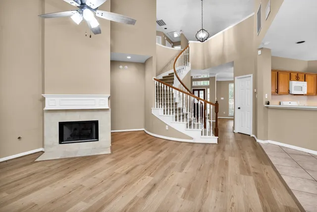 a view of an empty room with wooden floor fireplace and a window