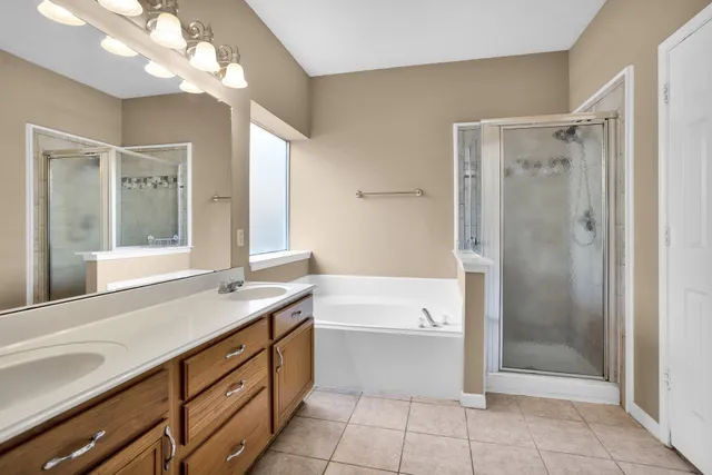 a bathroom with a bathtub shower sink vanity and mirror