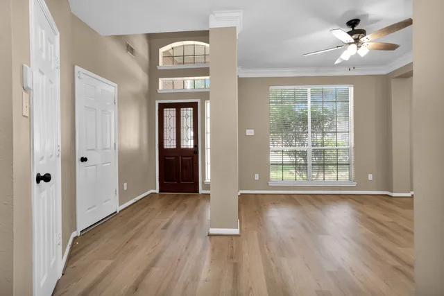 a view of an empty room with a window and wooden floor