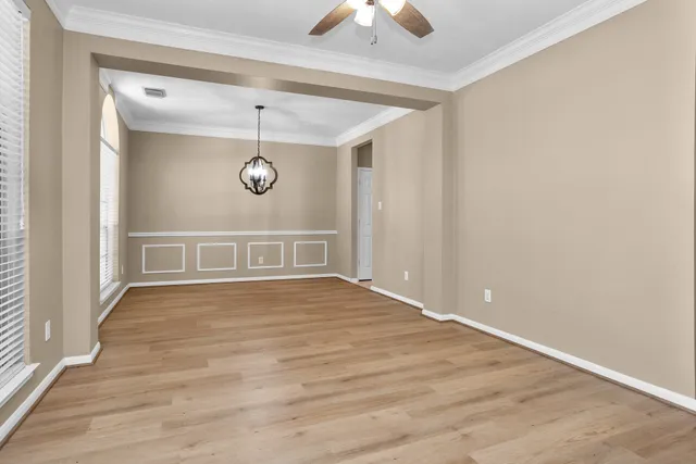 an empty room with wooden floor fan and windows