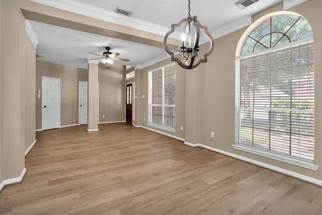 a view of a livingroom with a chandelier fan and windows