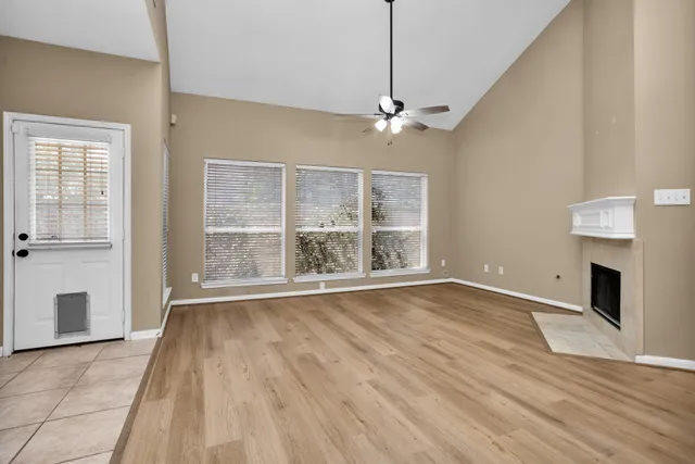 a view of an empty room with wooden floor fireplace and a window