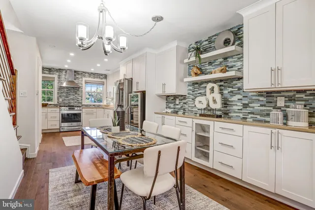 a kitchen with stainless steel appliances kitchen island granite countertop a table chairs sink and cabinets