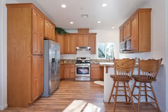 a kitchen with stainless steel appliances granite countertop a refrigerator and a stove top oven