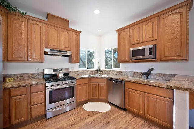 a kitchen with stainless steel appliances granite countertop wooden cabinets and a stove top oven
