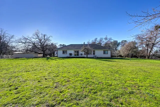 a aerial view of residential house with outdoor space and trees all around
