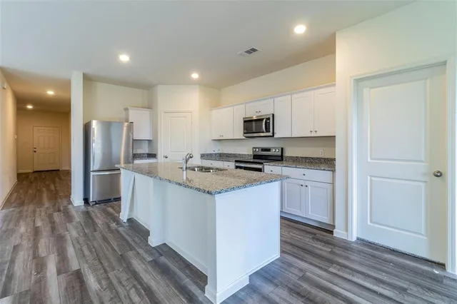 a kitchen with stainless steel appliances kitchen island granite countertop a stove top oven a sink and a refrigerator
