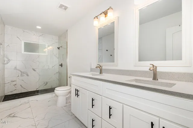 a bathroom with a granite countertop sink a toilet and a mirror