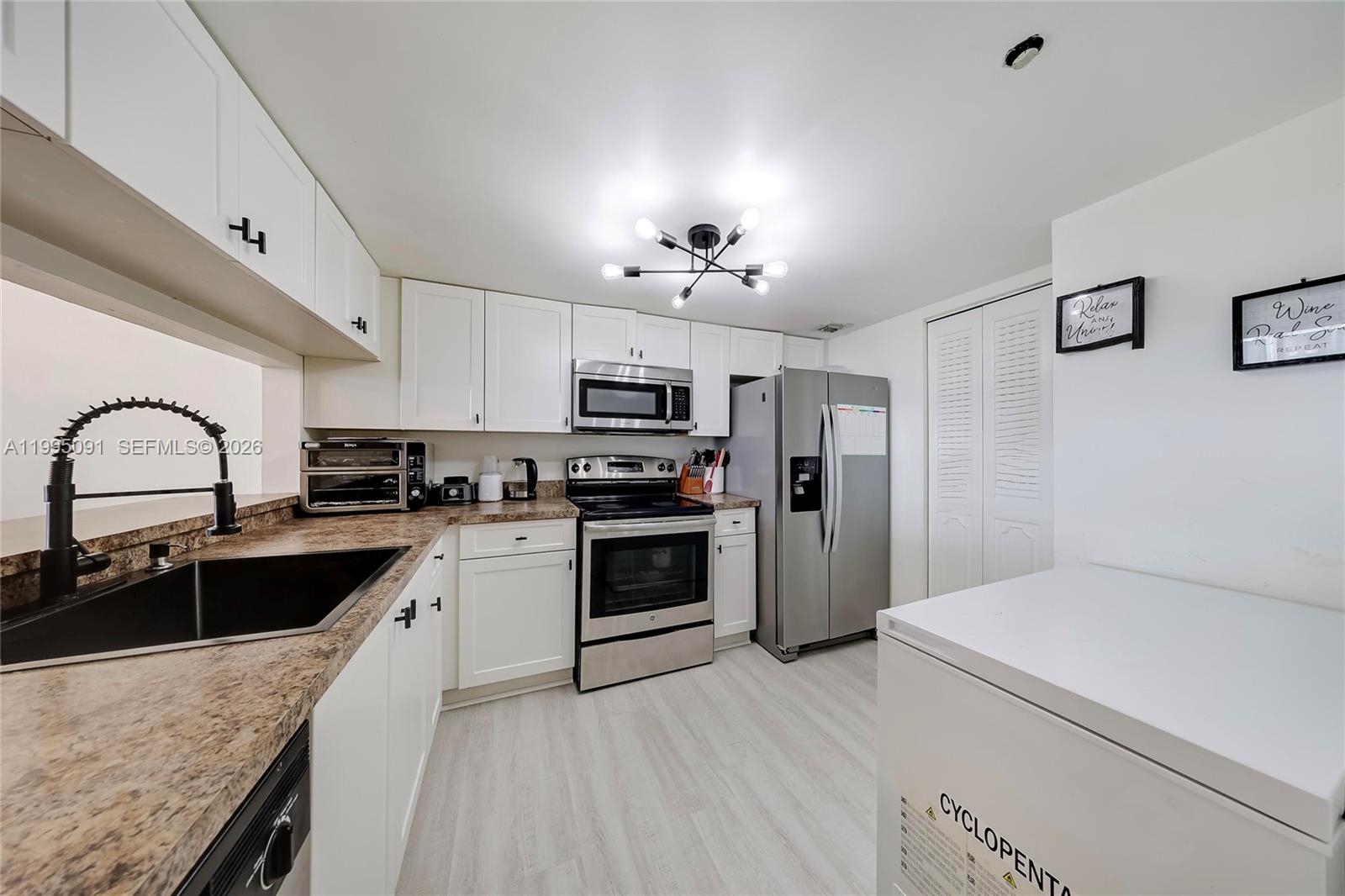 555 Northeast 15th Street, Unit 33G Miami, FL 33132 - Photo 6 of 18 a kitchen with granite countertop a sink stainless steel appliances and white cabinets
