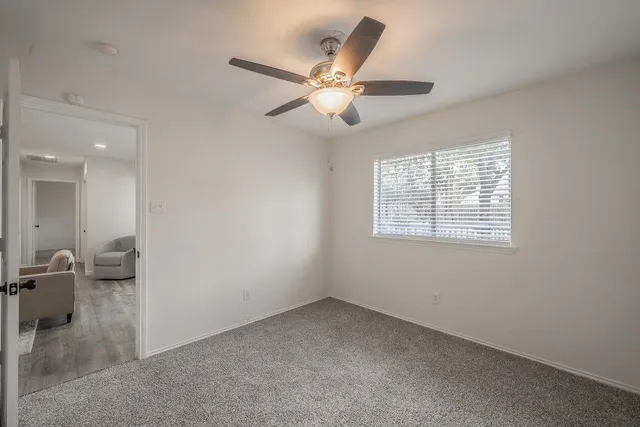 an empty room with a ceiling fan and a window