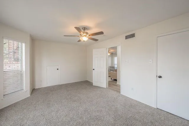 an empty room with a ceiling fan and a window