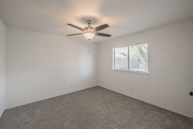 an empty room with a window and a fan