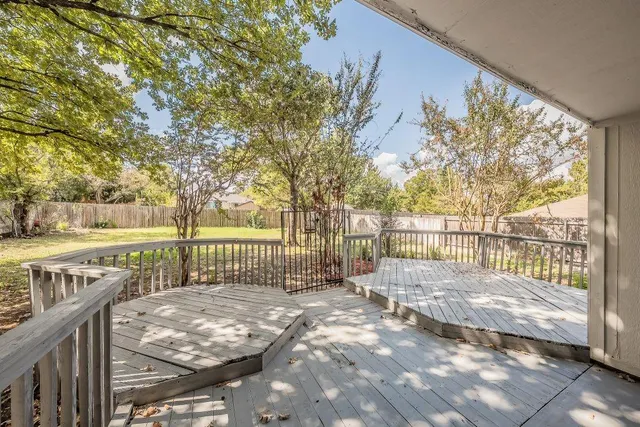 a view of a yard with trees and wooden fence