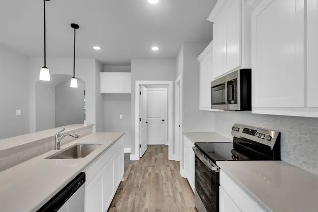a kitchen with stainless steel appliances white cabinets and wooden floor
