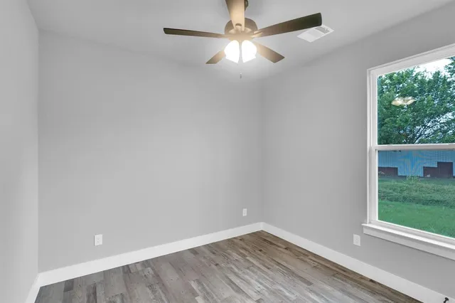 an empty room with a window and a fan