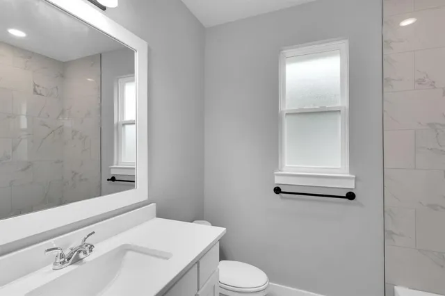 a bathroom with a sink a toilet and shower