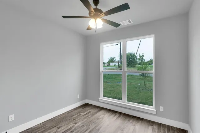 an empty room with wooden floor and windows