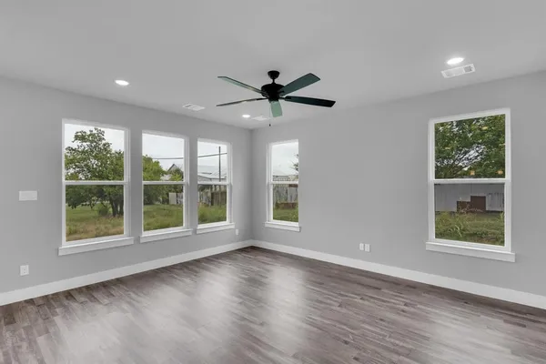 a view of an empty room with a window and wooden floor