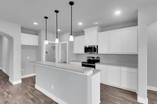 a kitchen with stainless steel appliances kitchen island a sink a stove a refrigerator and white cabinets