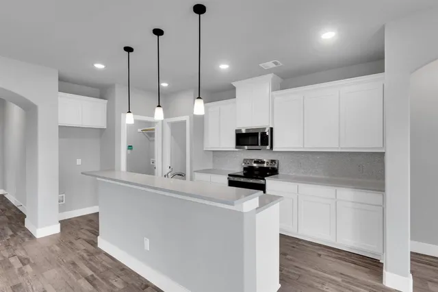 a kitchen with stainless steel appliances kitchen island a sink a stove a refrigerator and white cabinets