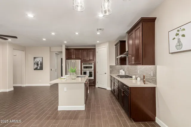 a large kitchen with stainless steel appliances kitchen island a large counter top a stove a chimney a sink and a refrigerator