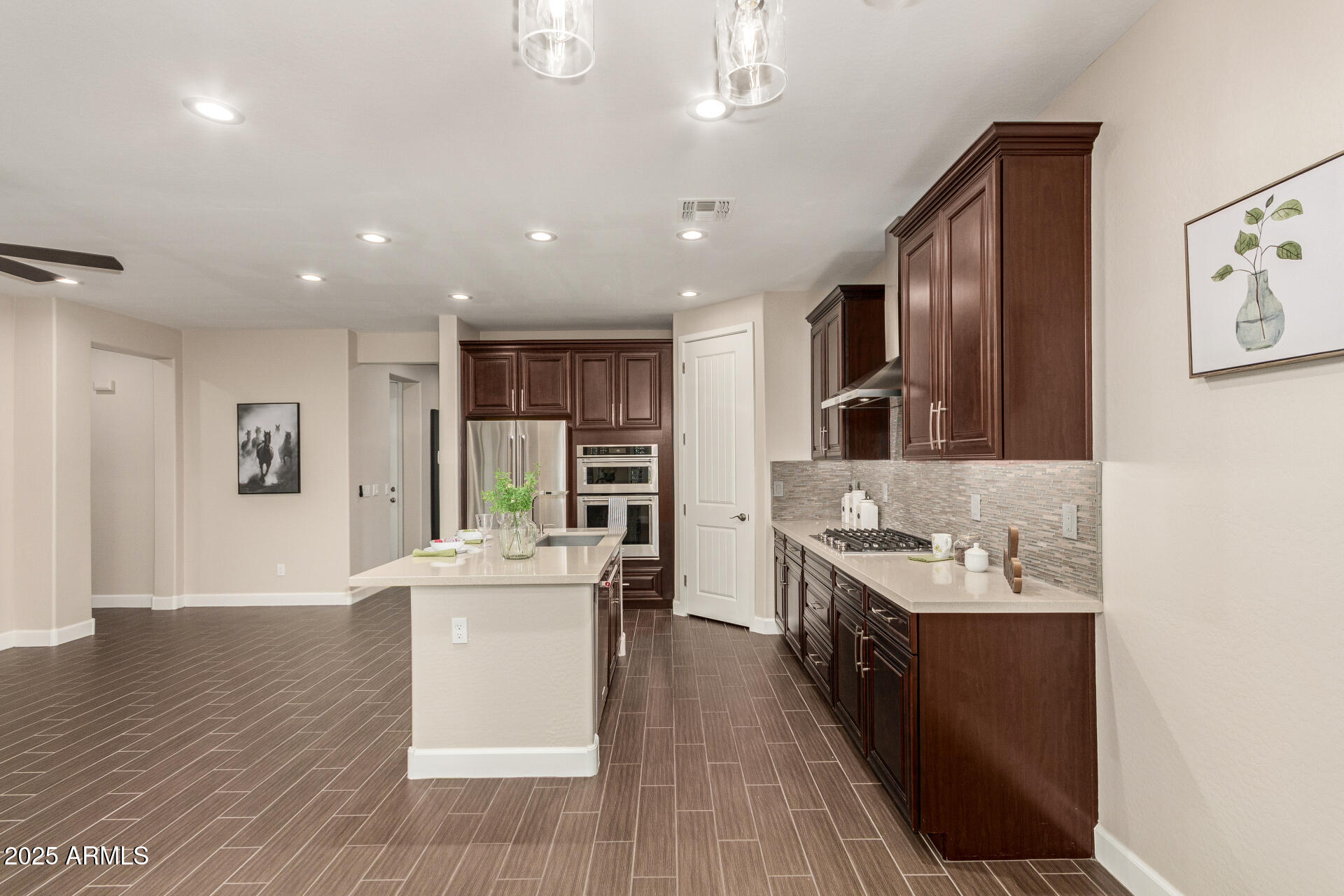 4312 East Rawhide Street Gilbert, AZ 85296 - Photo 8 of 24 a large kitchen with stainless steel appliances kitchen island a large counter top a stove a chimney a sink and a refrigerator