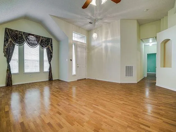 a view of empty room with wooden floor