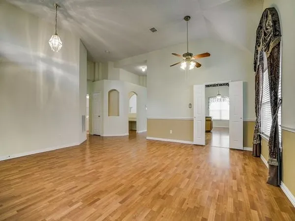 a view of a room with wooden floor a ceiling fan and window