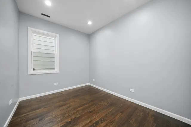 an empty room with wooden floor and window