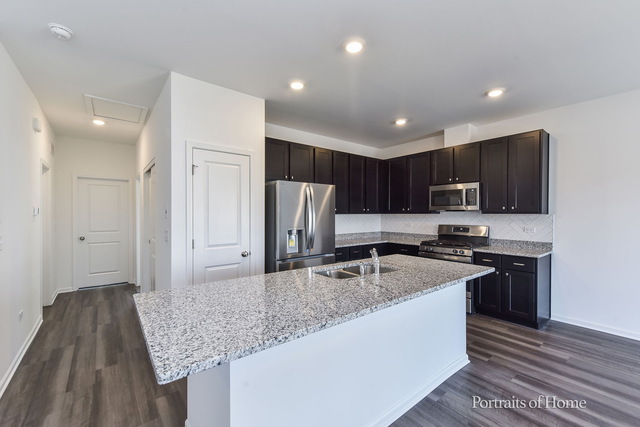 4189 Chelsea Manor Circle Aurora, IL 60504 - Photo 8 of 19 a kitchen with stainless steel appliances granite countertop a sink stove and refrigerator