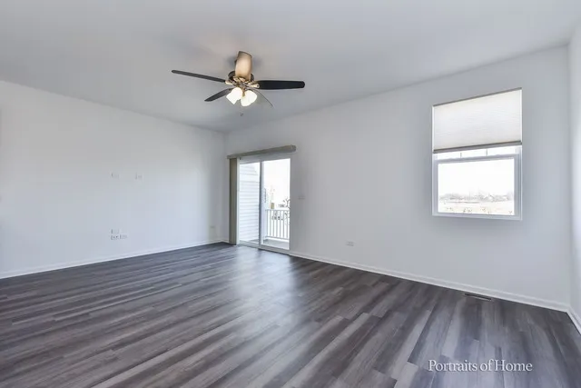an empty room with wooden floor fan and windows
