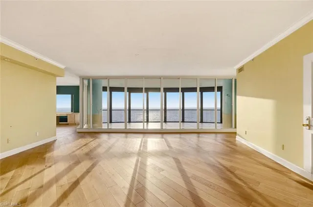 a view of an empty room with a window and wooden floor