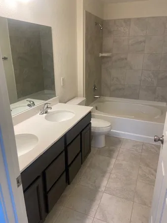 a bathroom with a double vanity sink toilet mirror and bathtub