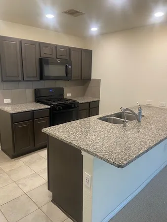 a kitchen with kitchen island granite countertop a sink cabinets and wooden floor