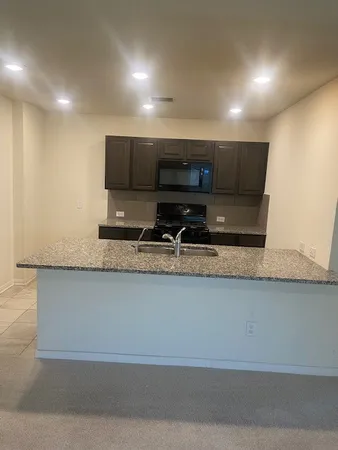 a view of kitchen with stainless steel appliances granite countertop sink and stove