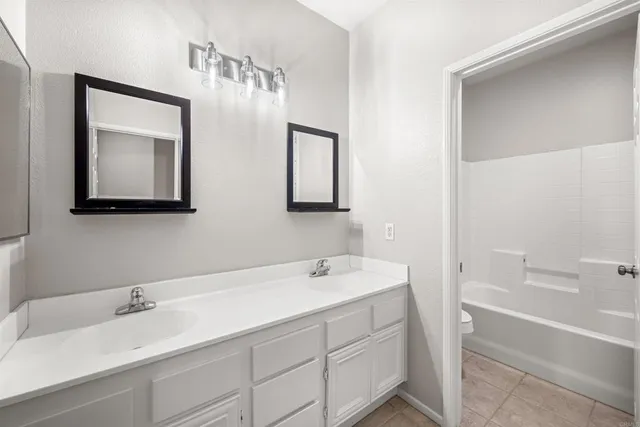 a bathroom with a double vanity sink mirror and bathtub
