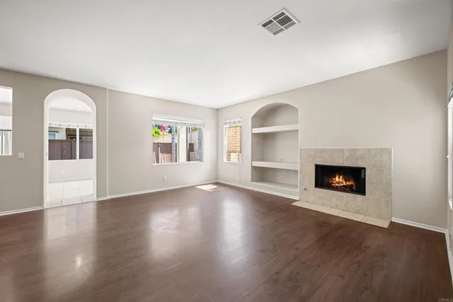 a view of an empty room with wooden floor fireplace and a window