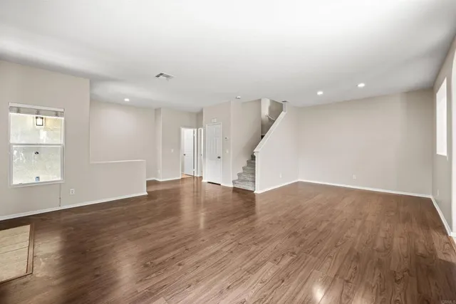an empty room with wooden floor and windows