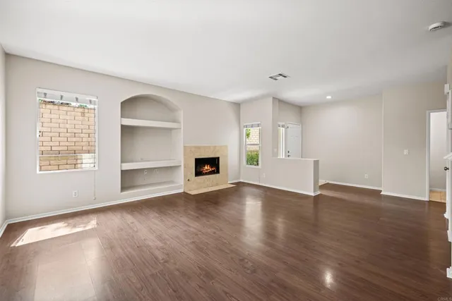 an empty room with wooden floor fireplace and windows